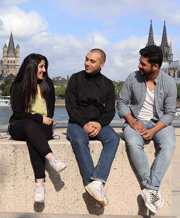 Jugendforum Köln-Team sitzt auf einer Mauer im Hintergrund ist der Kölner Dom zu sehen.